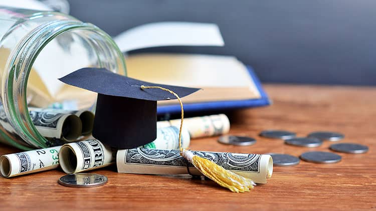 A graduation cap sitting on American money